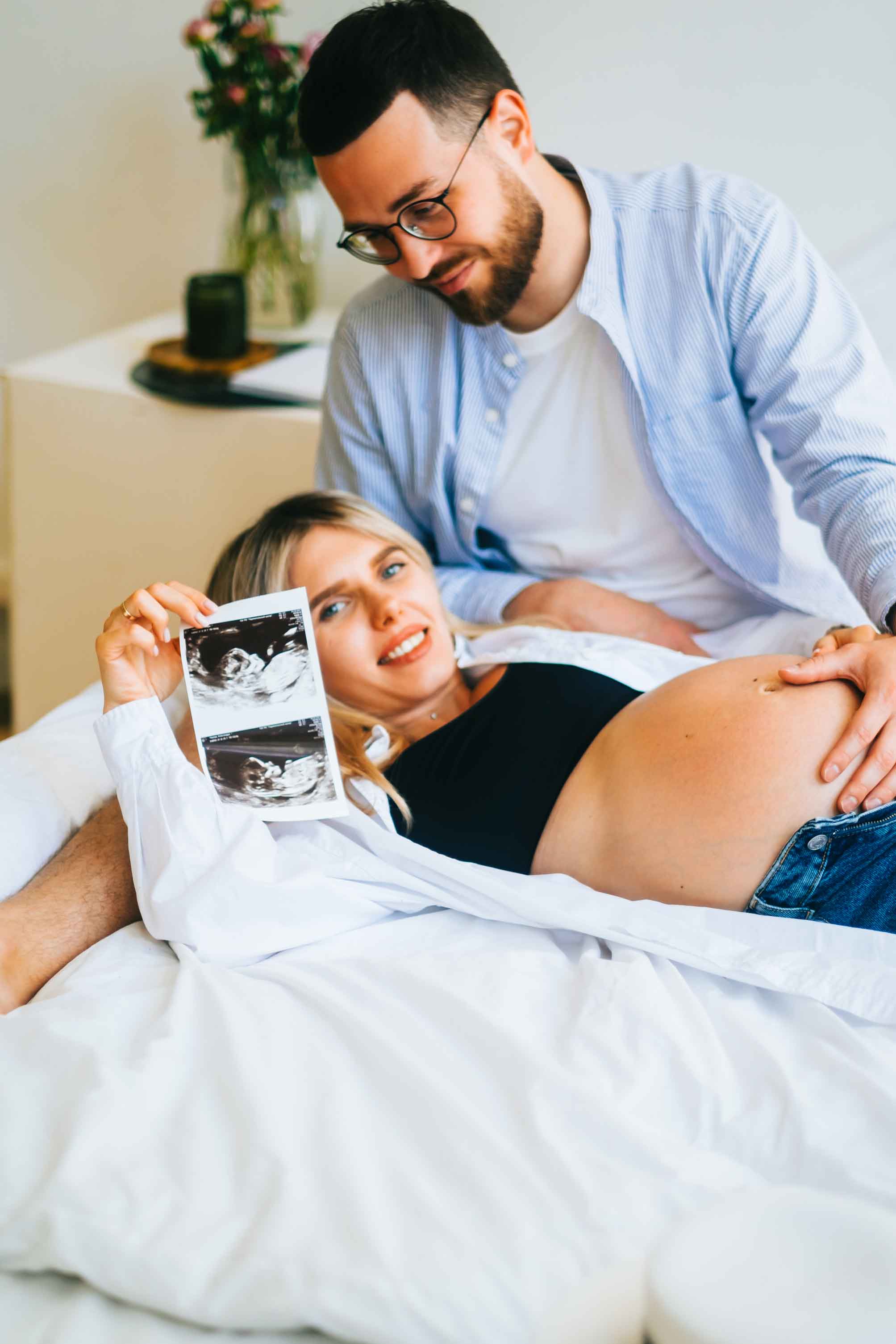 Pregnant couple together with wife holding up her 2D Ultrasound Images