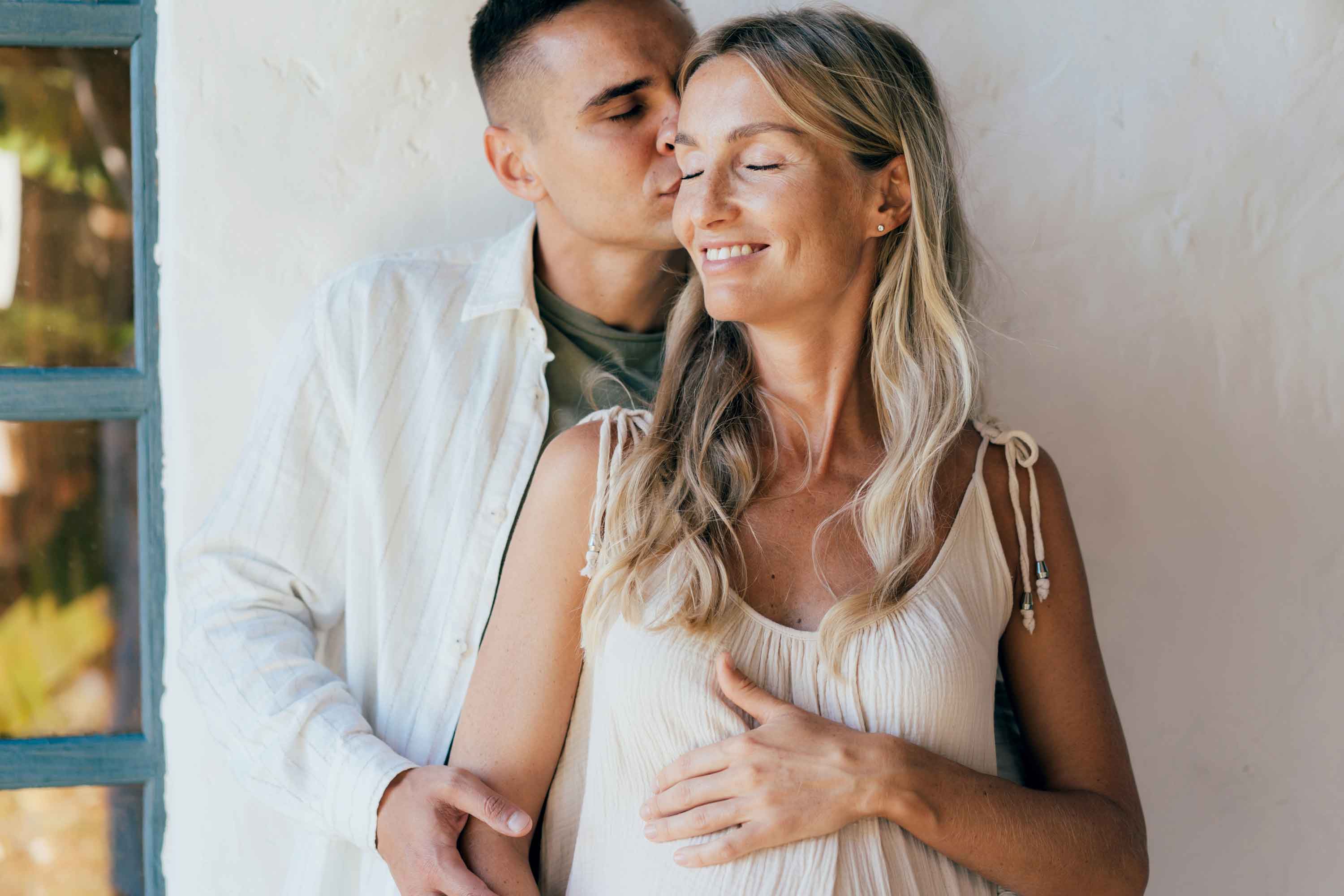 Husband kissing his pregnant wife as she hold her belly