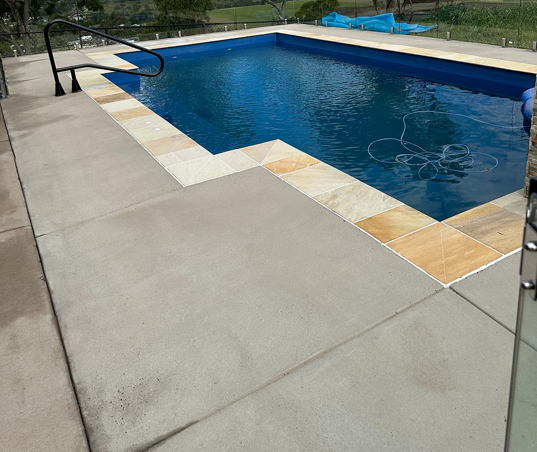 Clean poolside area with bright tiles and clear blue water, showing a spotless surface after pressure washing.
