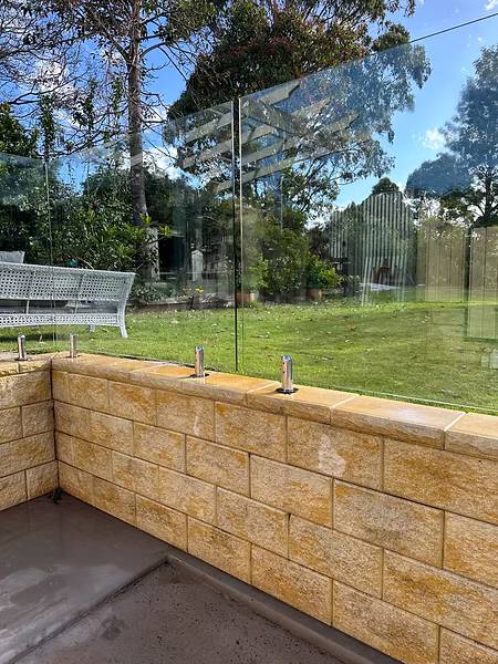 Restored retaining wall and glass fence after professional pressure washing by Hosed Building and Gutter