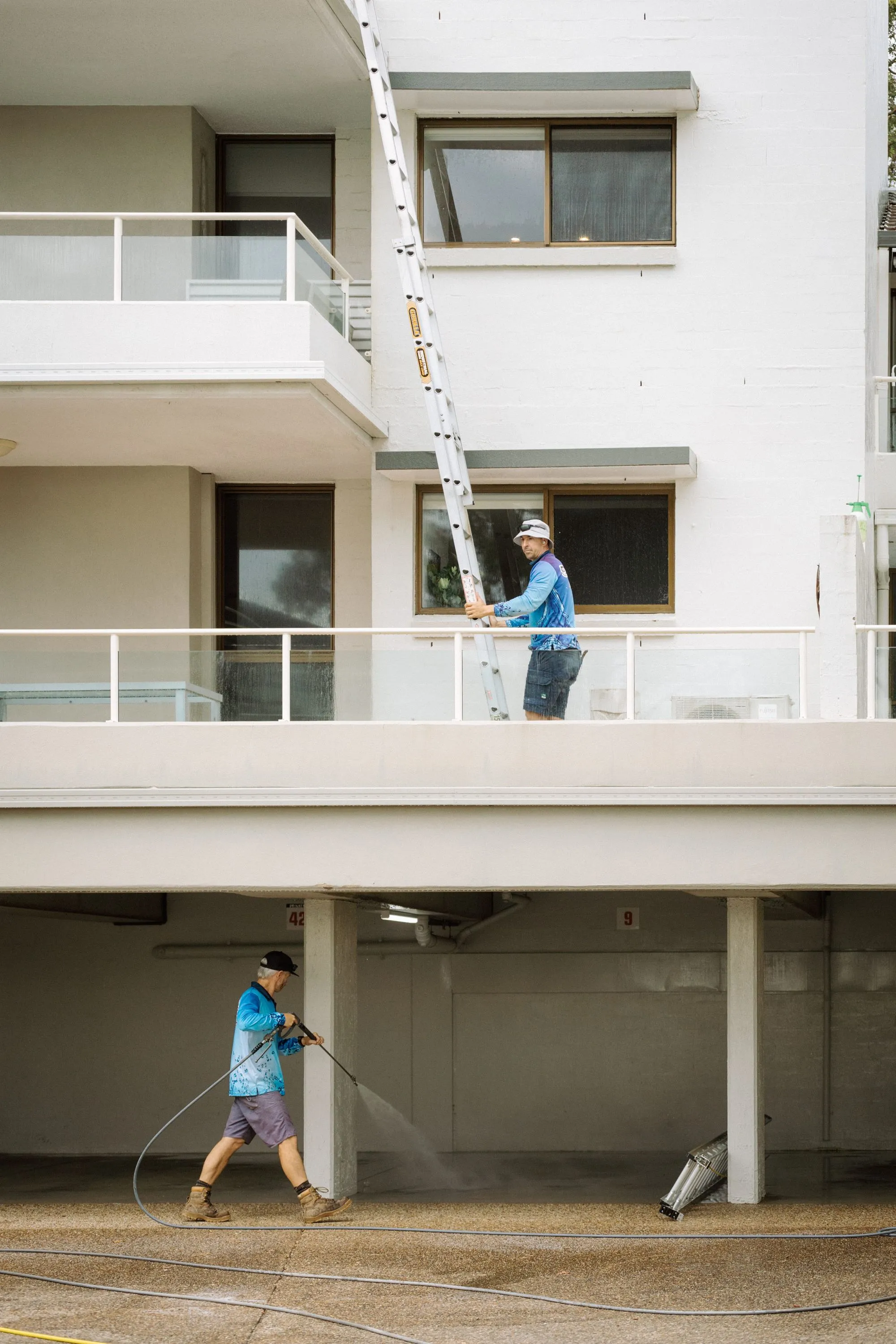Hosed Building and Gutter team performing residential pressure washing and exterior cleaning on apartment building