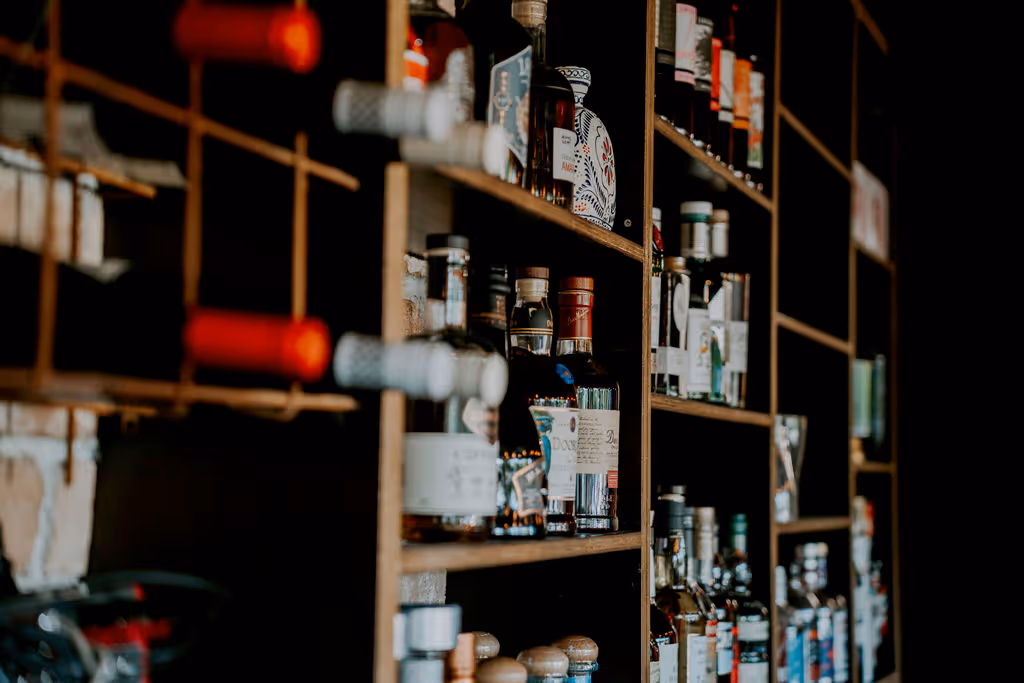 Shelves filled with various bottles of liquor and wine in a dimly lit bar setting.