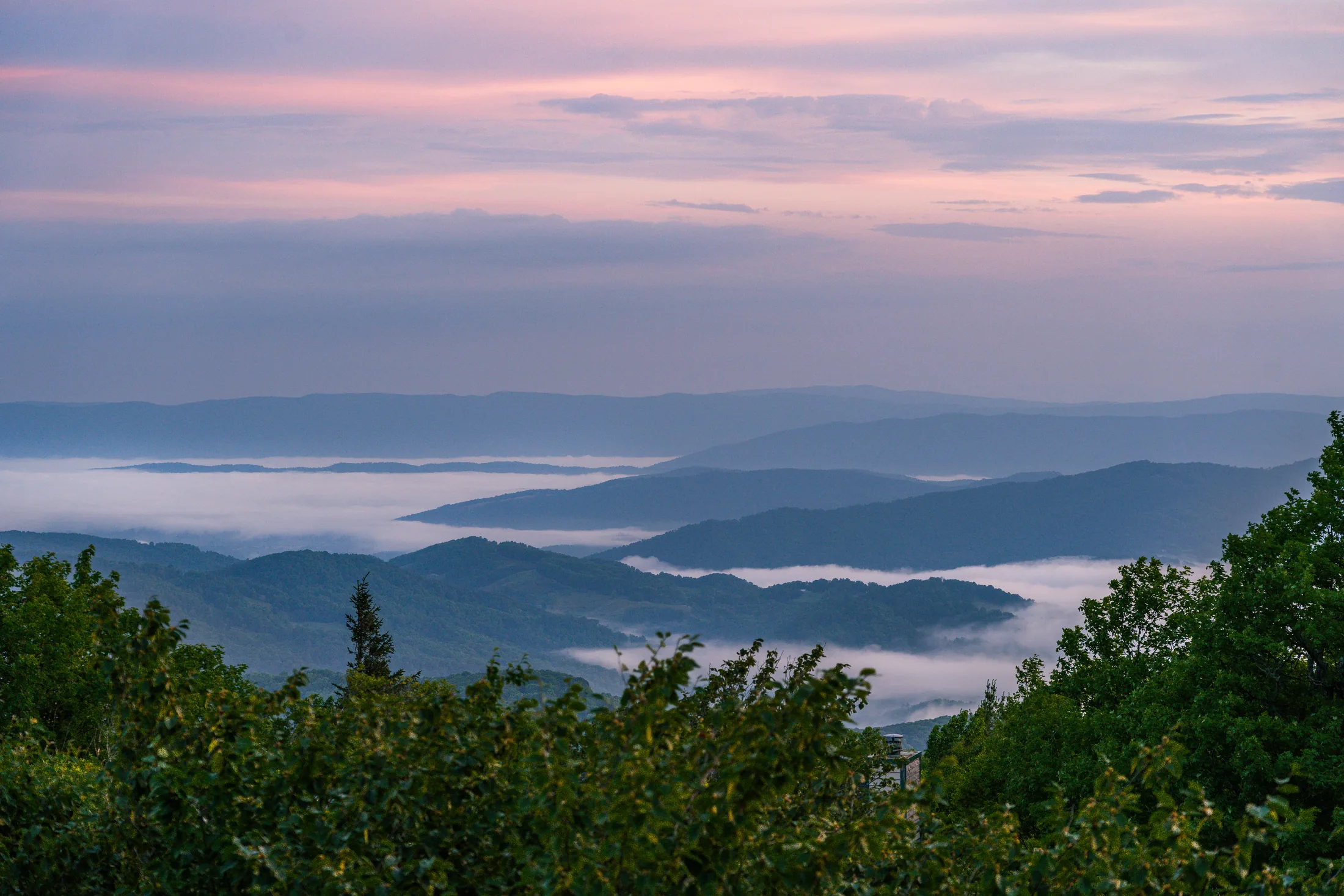 Mist-filled mountain valleys beneath a pink morning sky