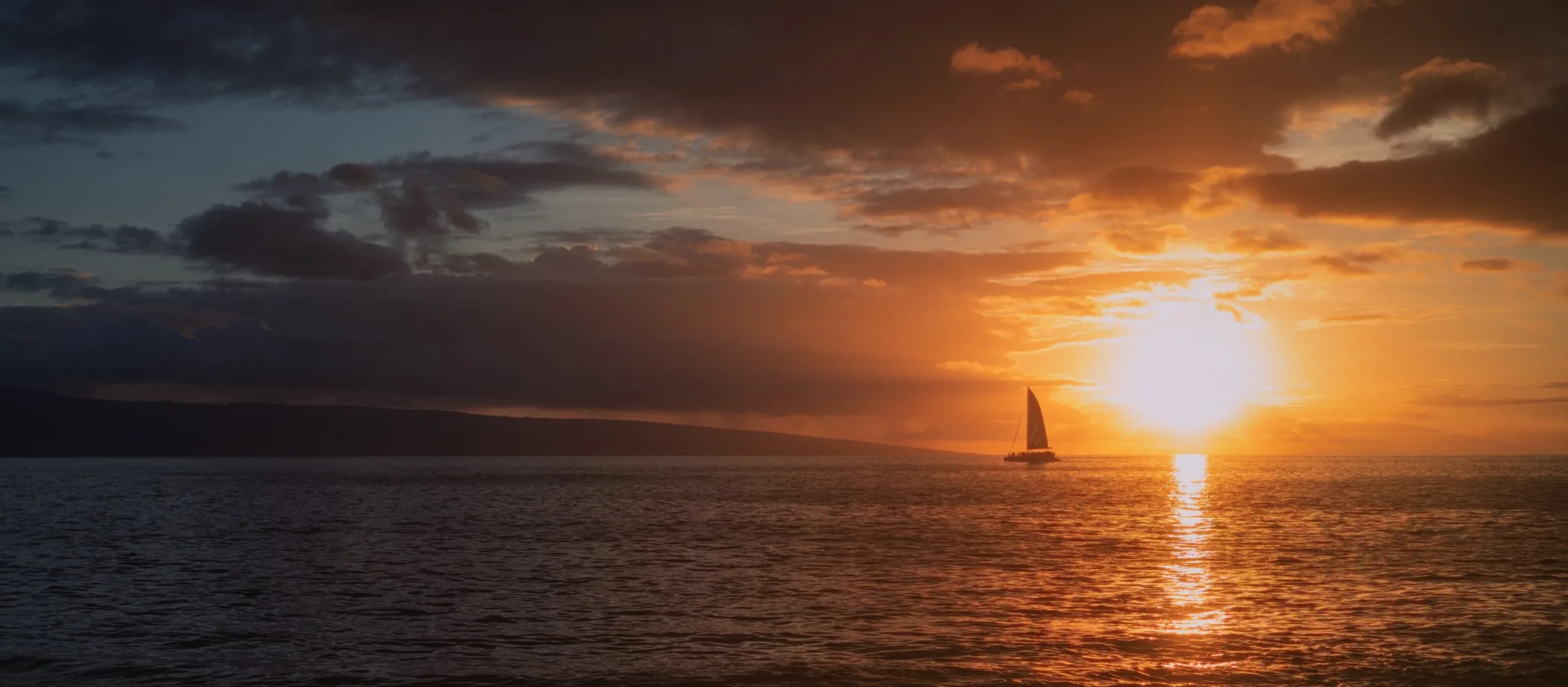 Sailboat on the water beneath a glowing sunset