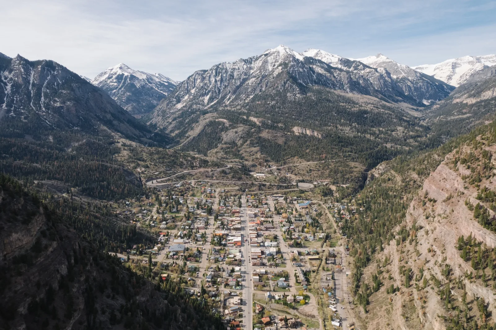 Aerial view of a town nestled beneath rugged mountain peaks
