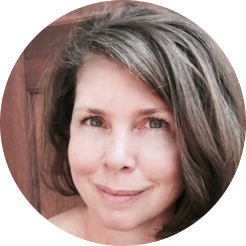 Close-up portrait of a woman with shoulder-length gray and brown hair smiling gently.