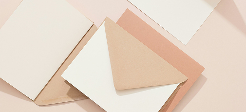 Several beige and white envelopes and cards arranged on a light surface.