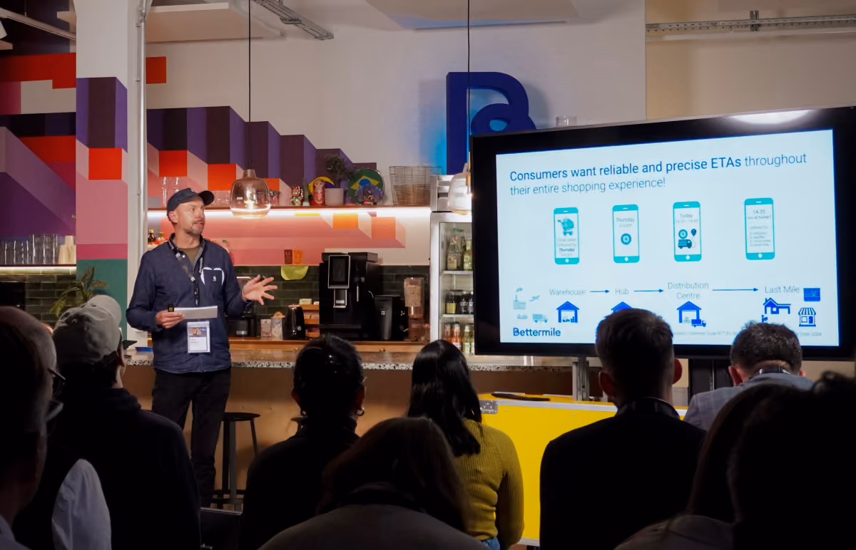 Speaker presenting delivery ETA research to a seated audience at the Last Mile Delivery Meetup