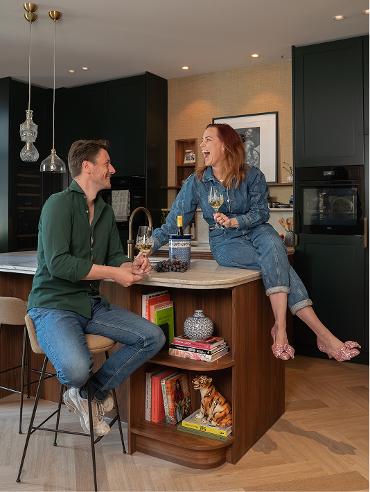 Twee mensen die gezellig aan de bar zitten in huis.