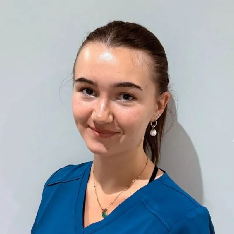 A woman in a blue shirt is smiling at the camera.