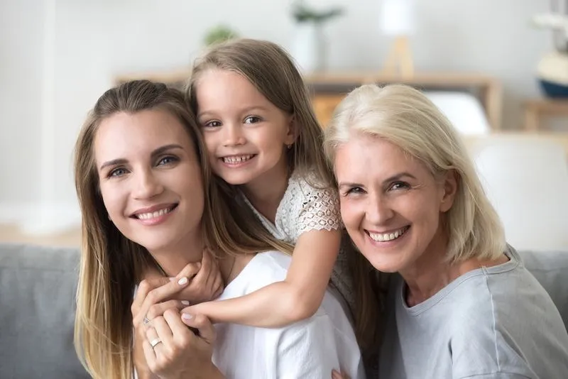 A two woman and and a girl are smiling for the camera.