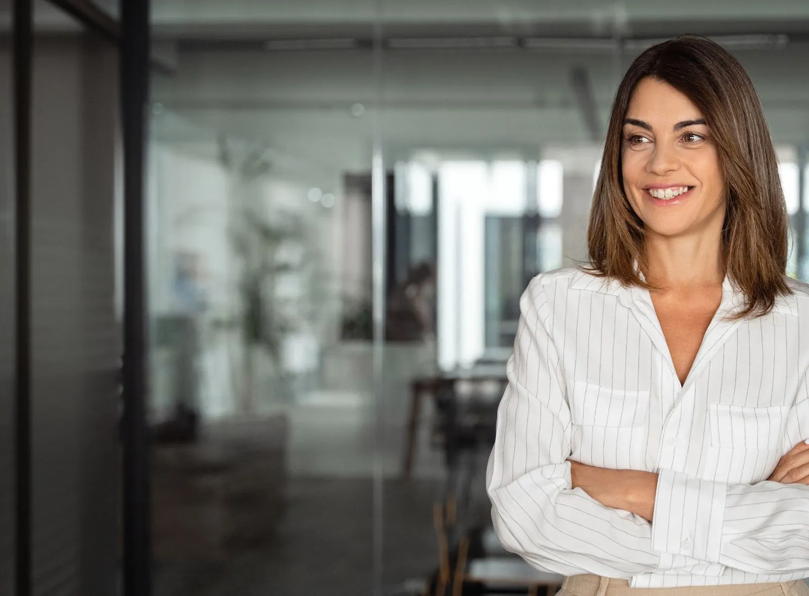 A woman standing with her arms crossed in a room.