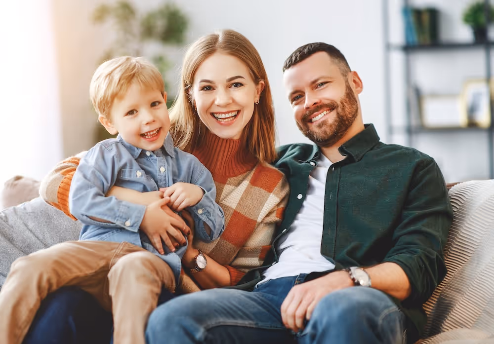 A man and woman sitting on a couch with a child.
