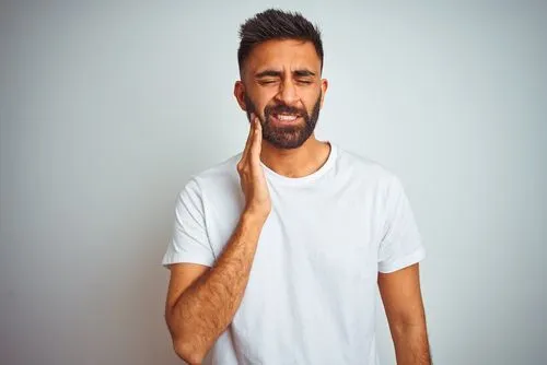 A man holding his hand to his face in discomfort.