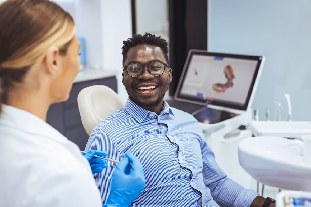 A man sitting in a dentist chair smiling.