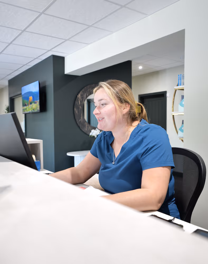 A woman sitting at a reception desk using a computer.