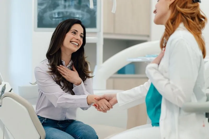 Two women shaking hands in a dental office.