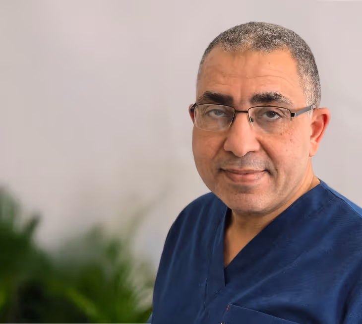 A man wearing glasses and a blue scrub top.