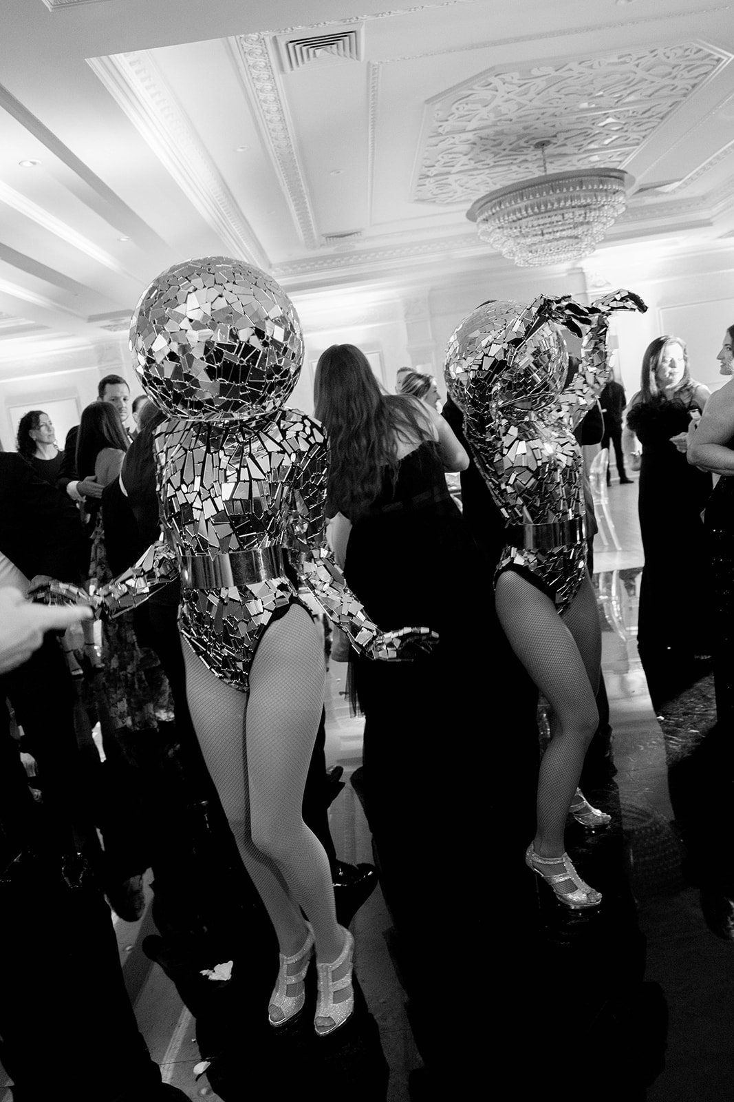 Two performers wearing mosaic mirror ball costumes with fishnet stockings at a formal event.