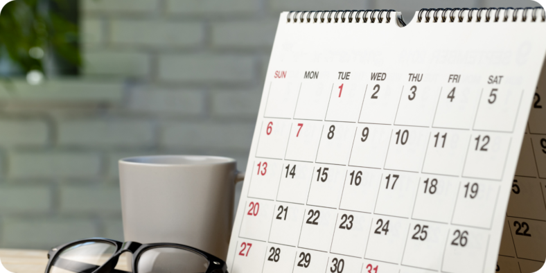 kalenteri pöydällä, vieressä silmälasit ja kahvikuppi
