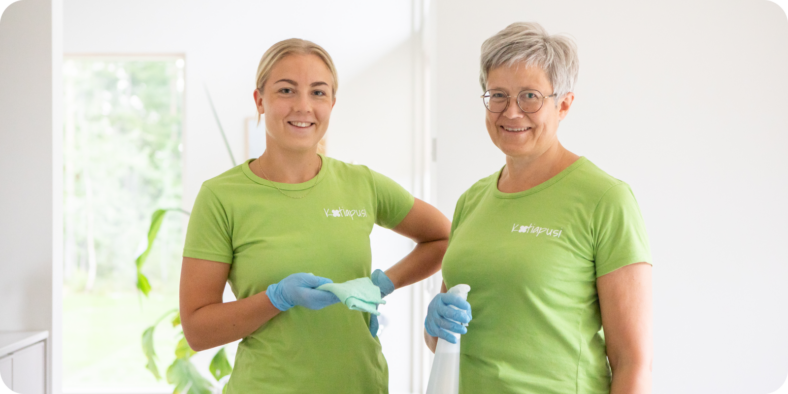 Kotiapusi Oy:n kaksi työntekijää hymyilemässä kameralle. Heillä on päällään vihreät työpaidat Kotiapusi-tekstillä.