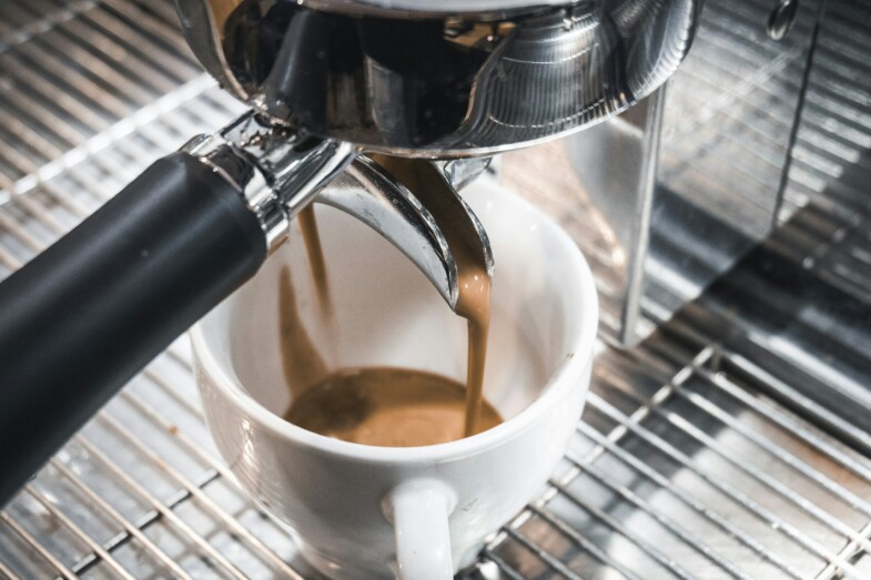 Espresso-kahvia valuu valkoiseen kuppiin kahvinkeittimen portafilterista