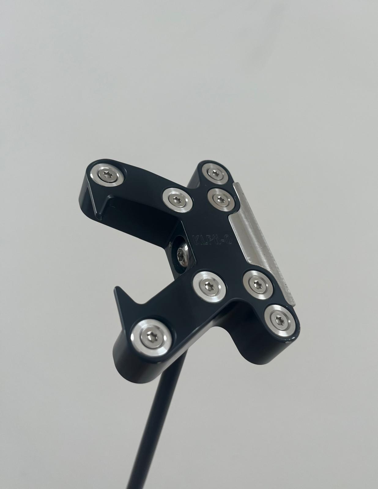 Close-up of a black metal device with several visible screws and a cable attached underneath.