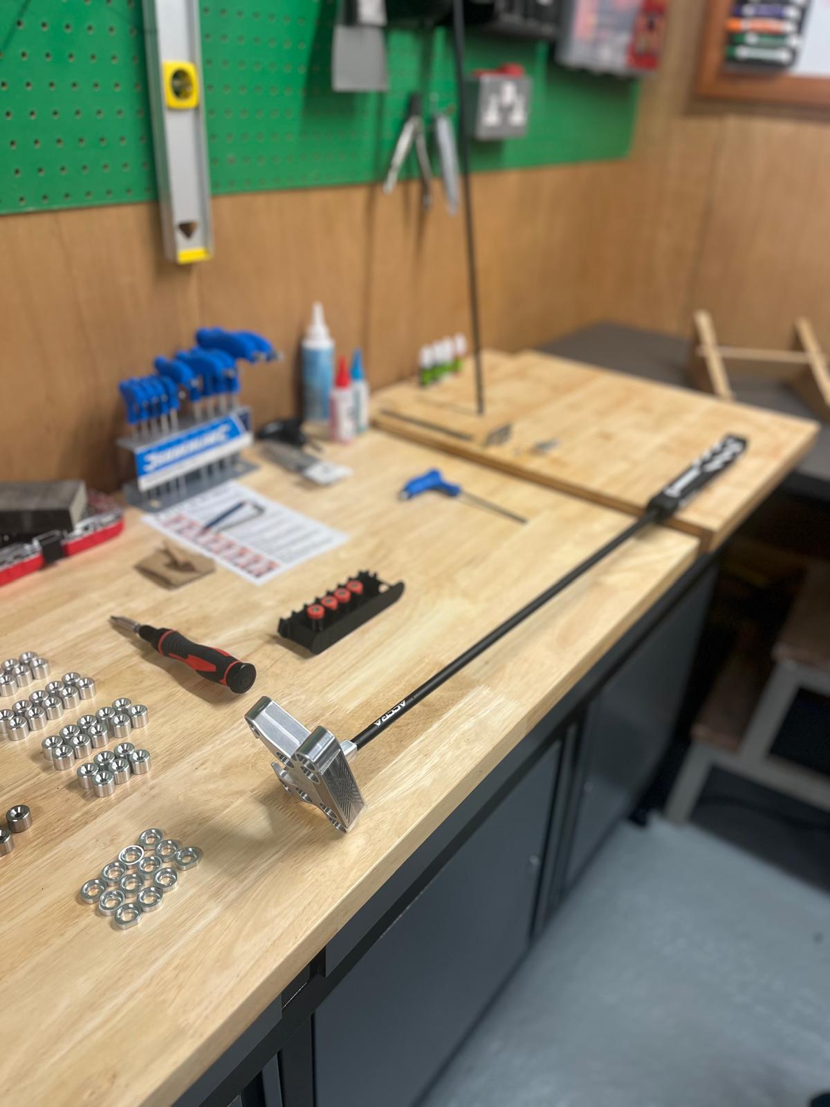 Workshop bench with hex keys, a screwdriver, metal washers, and a long tool with a metal head.