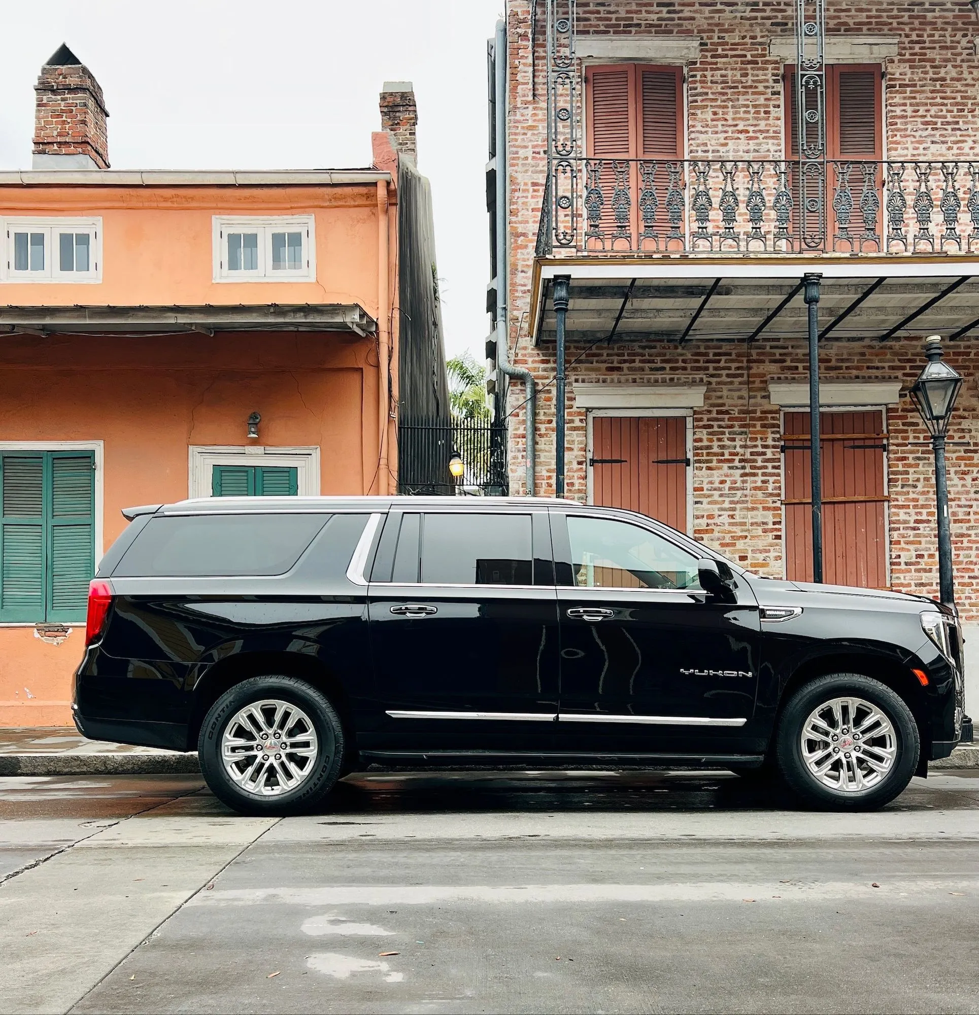 NOLA Black Car SUV on a French Quarter street with balconies and colorful Creole townhouses