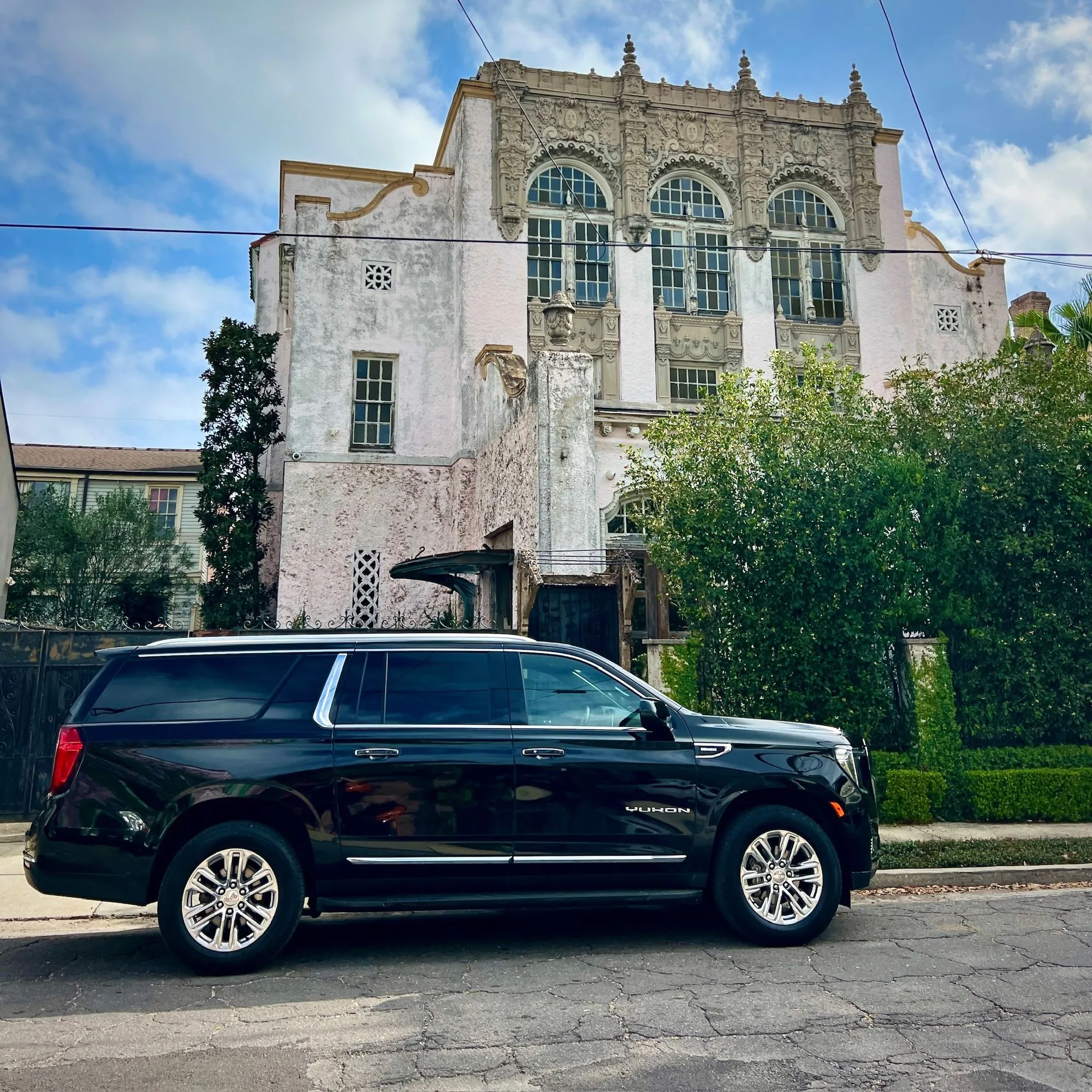 Black executive SUV parked outside a historic building in New Orleans