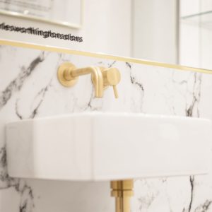 MARBLE AND BRASS DETAILING | A refined vanity unit at the Charles Worthington flagship salon, featuring a wall-mounted brushed brass tap and mixer set against a marble backsplash.