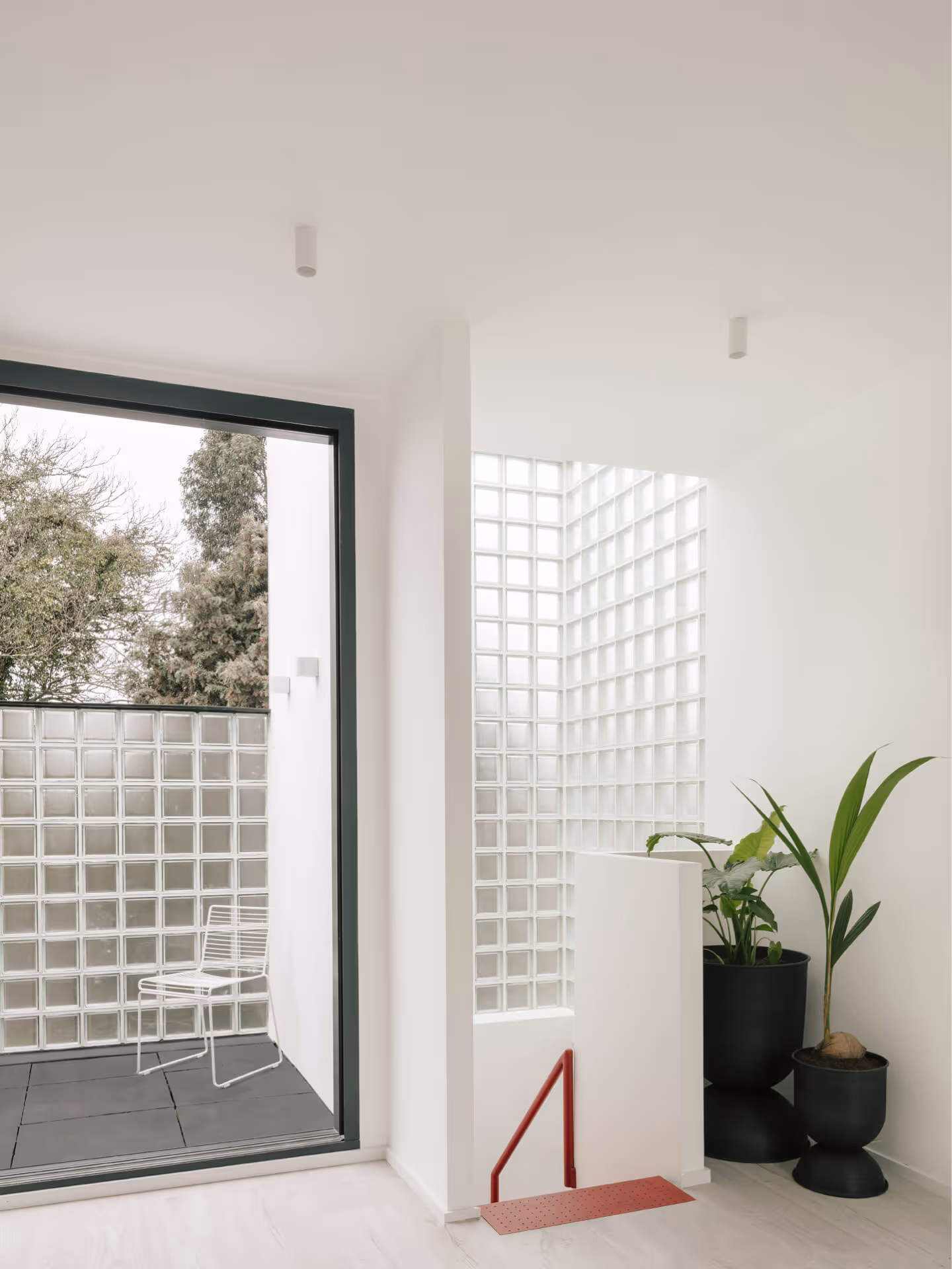 LIGHT-FILLED UPPER LANDING | Maryland House’s first-floor landing opens to a glass block wall and terrace, flooding the interior with natural light and creating a seamless connection between indoor and outdoor spaces.