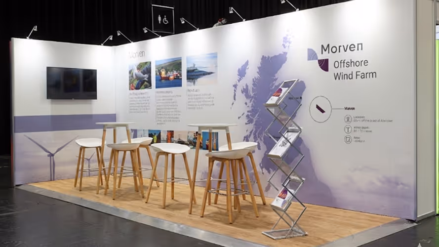 Exhibition booth with high stools, tables, brochure stand, and wall display for Morven Offshore Wind Farm featuring a map of Scotland.