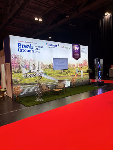 Trade show booth promoting Evkeeza and Ultomiris with slogan about breaking through very high LDL-C levels, featuring a golf course backdrop and decorative green turf.