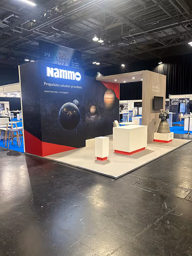 Exhibition booth for Nammo, a propulsion solution provider, featuring a space-themed backdrop with planets and white display stands.