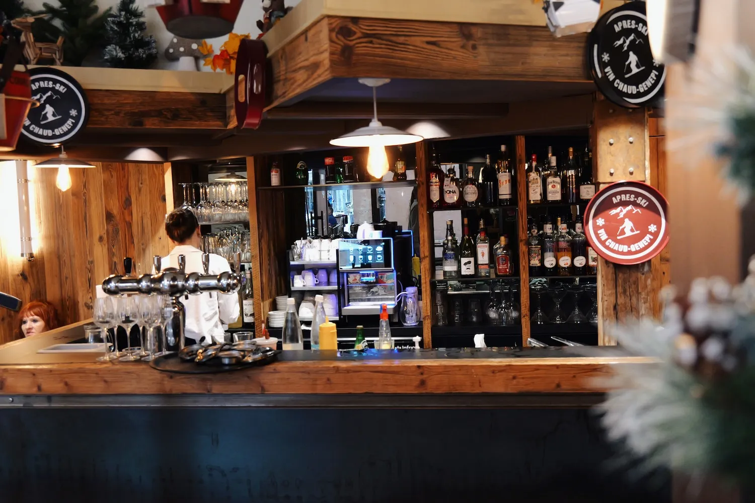 Bar du restaurant en bois, avec bouteilles et enseignes après-ski vin chaud génépi