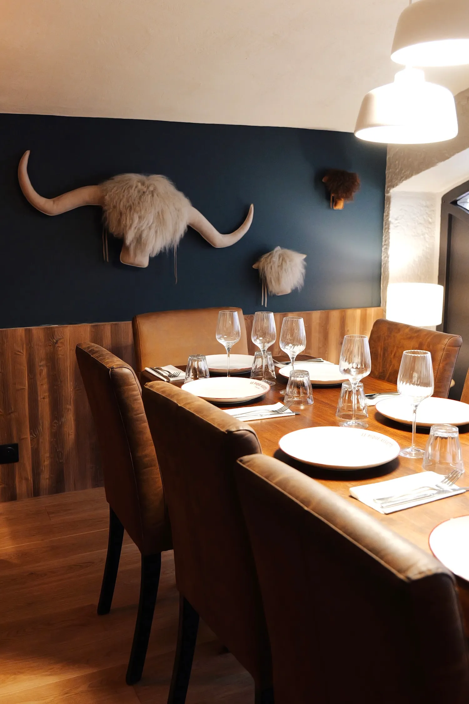 Salle au mur bleu avec tête de vache Highland et grande table dressée, restaurant Le Pique Assiette