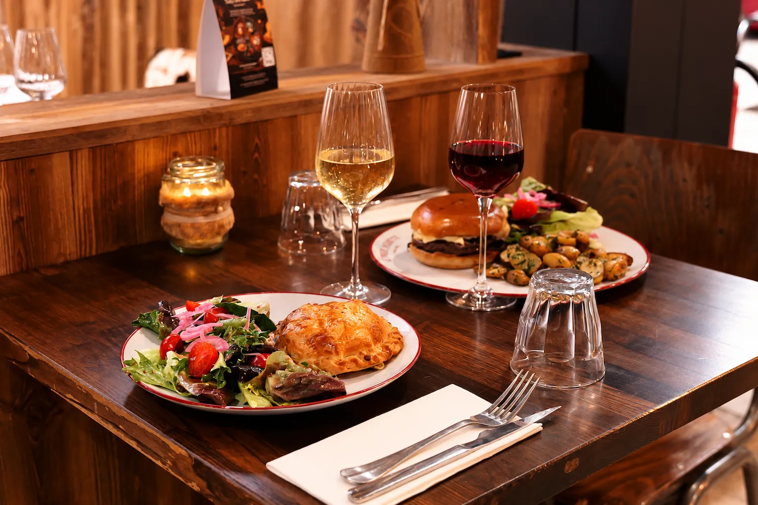 Burger au fromage avec pommes de terre persillées et assiette de salade sur une table en bois