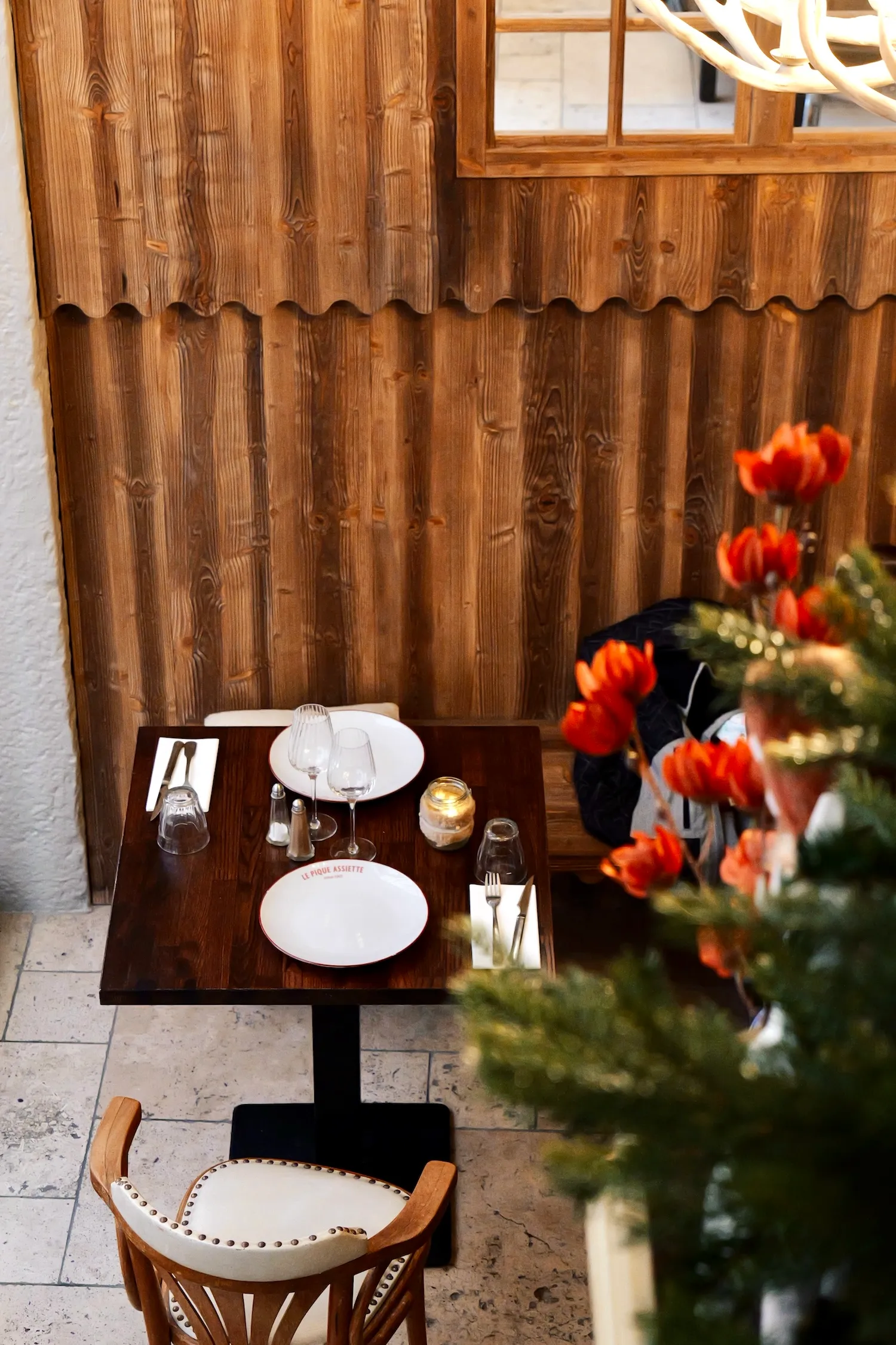 Table dressée contre un mur en bois avec sapin et fleurs au restaurant savoyard Le Pique Assiette, Vieux Lyon