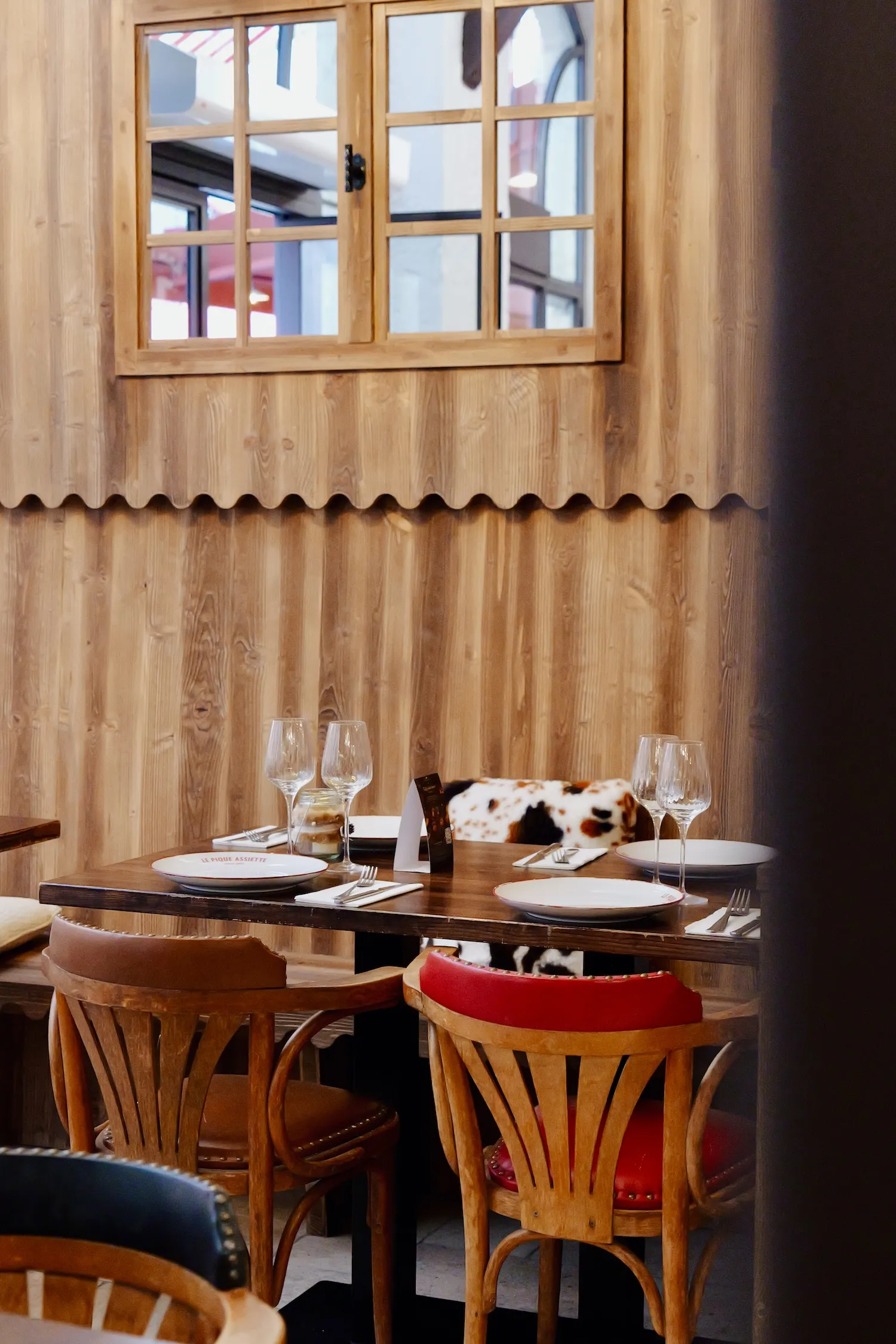 Table dressée près d'une fenêtre dans la salle du Pique Assiette, boiseries en bois clair, restaurant à privatiser dans le Vieux Lyon