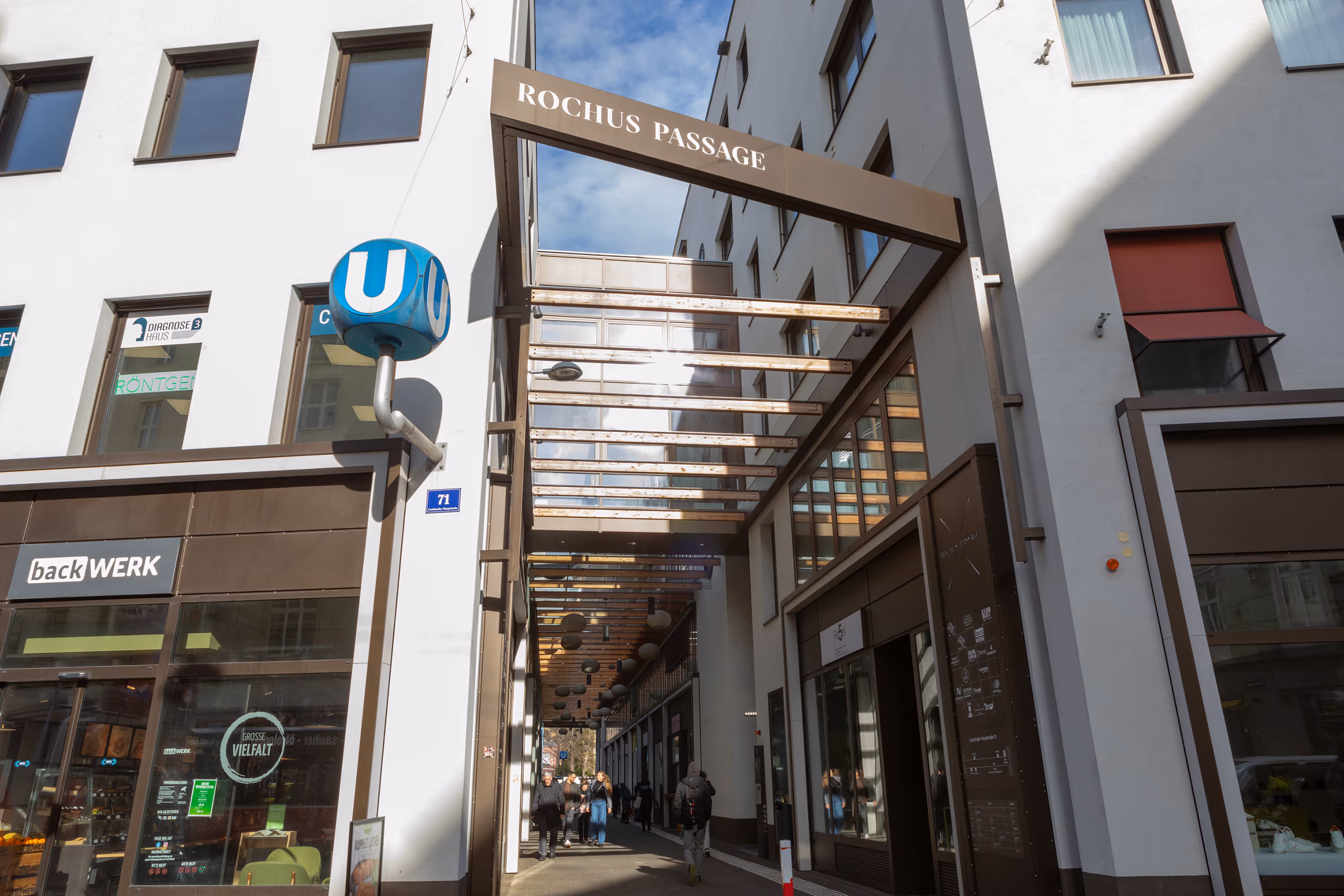 Eingang zur Zahnarztpraxis Dr. Renate Schaudy bei der Rochus Passage mit Glasdach und U-Bahn-Symbol.