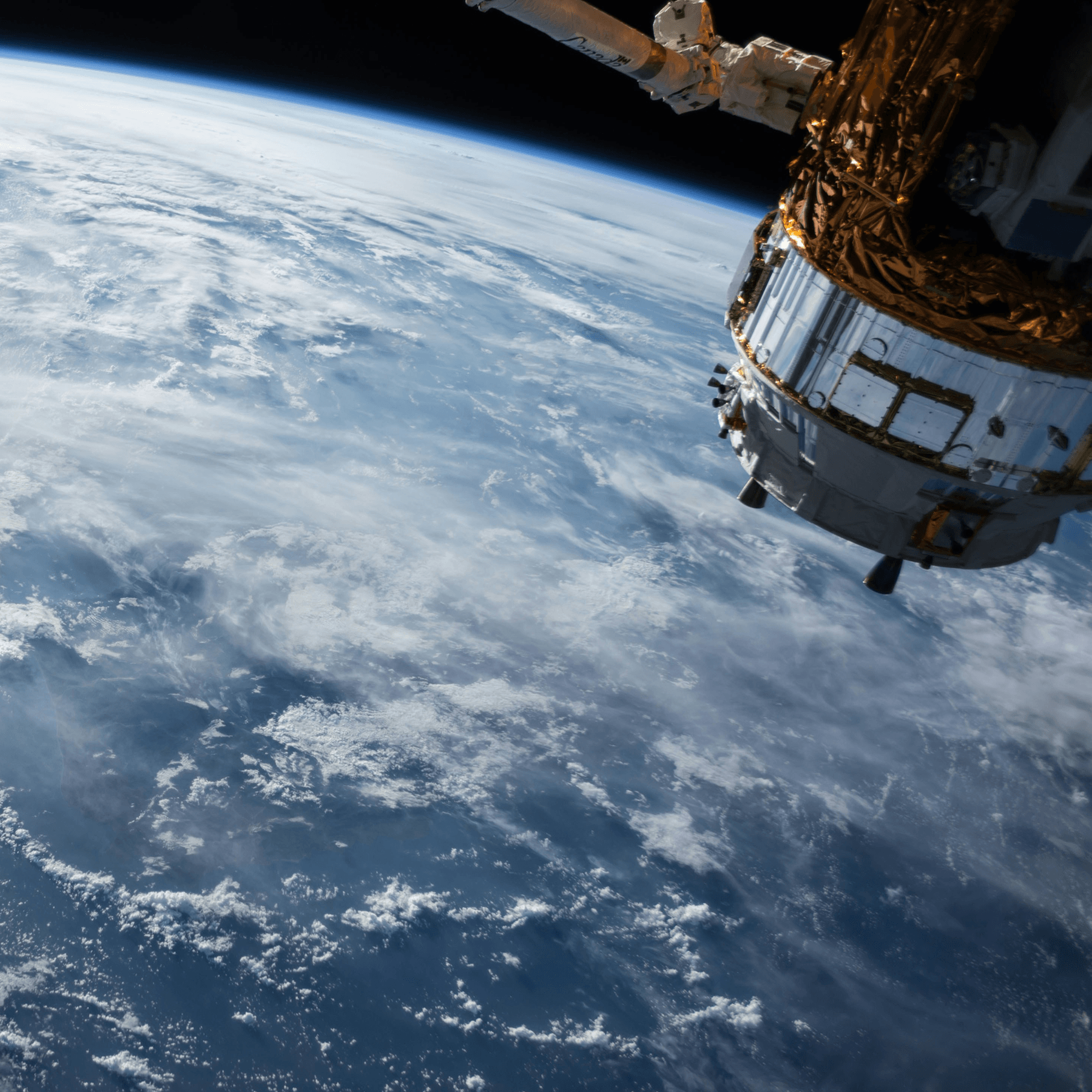 Satellite orbiting Earth with cloud-covered blue oceans visible below in space.