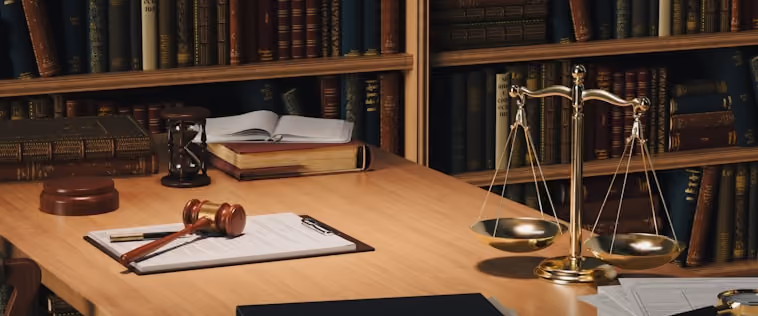 Un bureau avec un marteau de juge, un sablier, une balance de justice et des livres anciens.