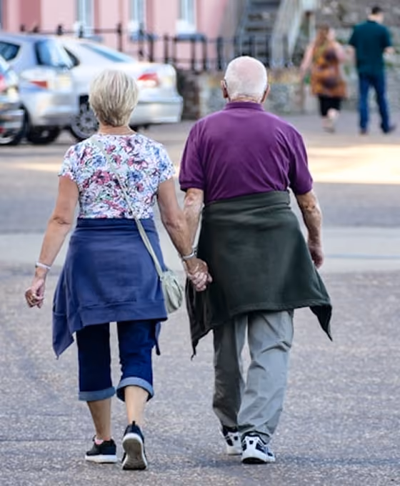 Un couple âgé marchant main dans la main dans une rue urbaine en arrière-plan flou.