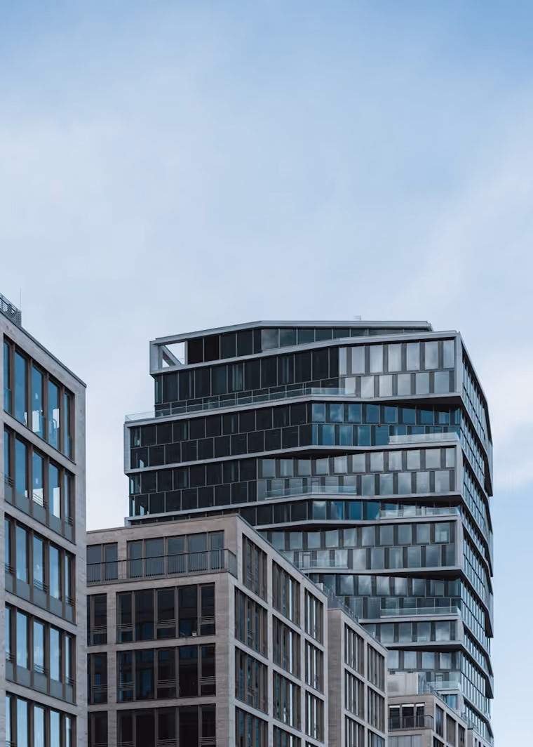 Bâtiments commerciaux modernes en verre et béton sous un ciel bleu clair.
