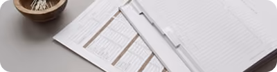 Vue rapprochée d'un bureau avec un porte-documents, un carnet et un bol en bois avec des crayons.