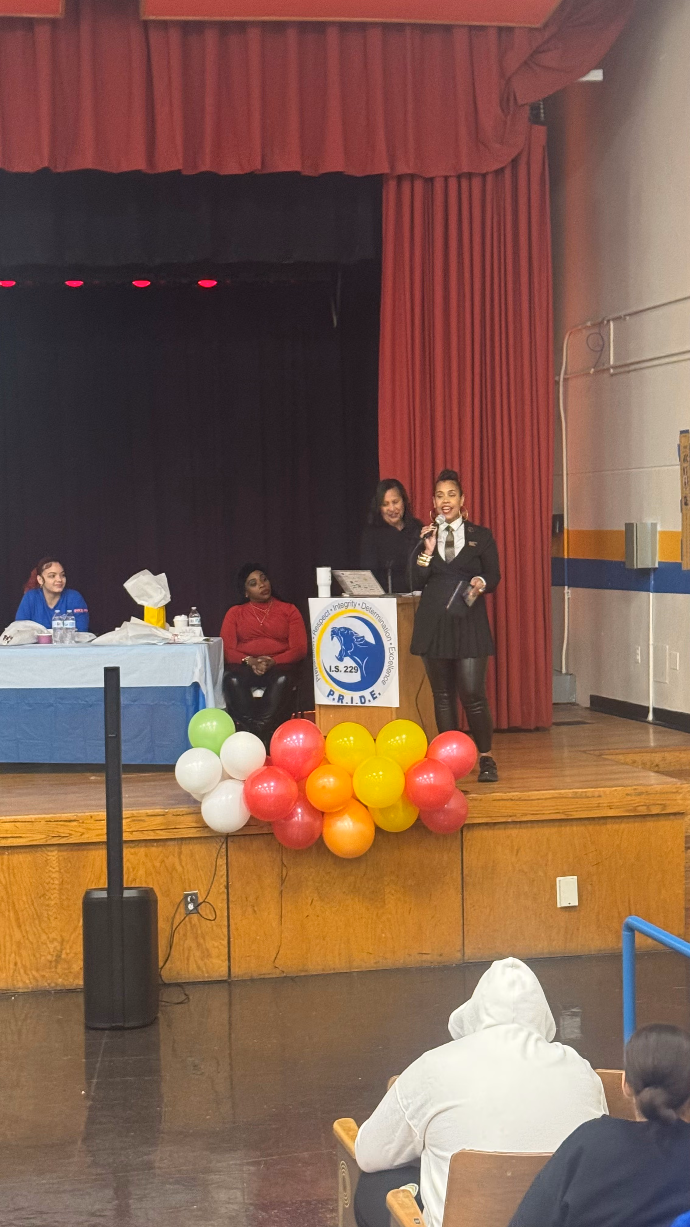 Speaker at podium during IS 229 PRIDE school assembly event