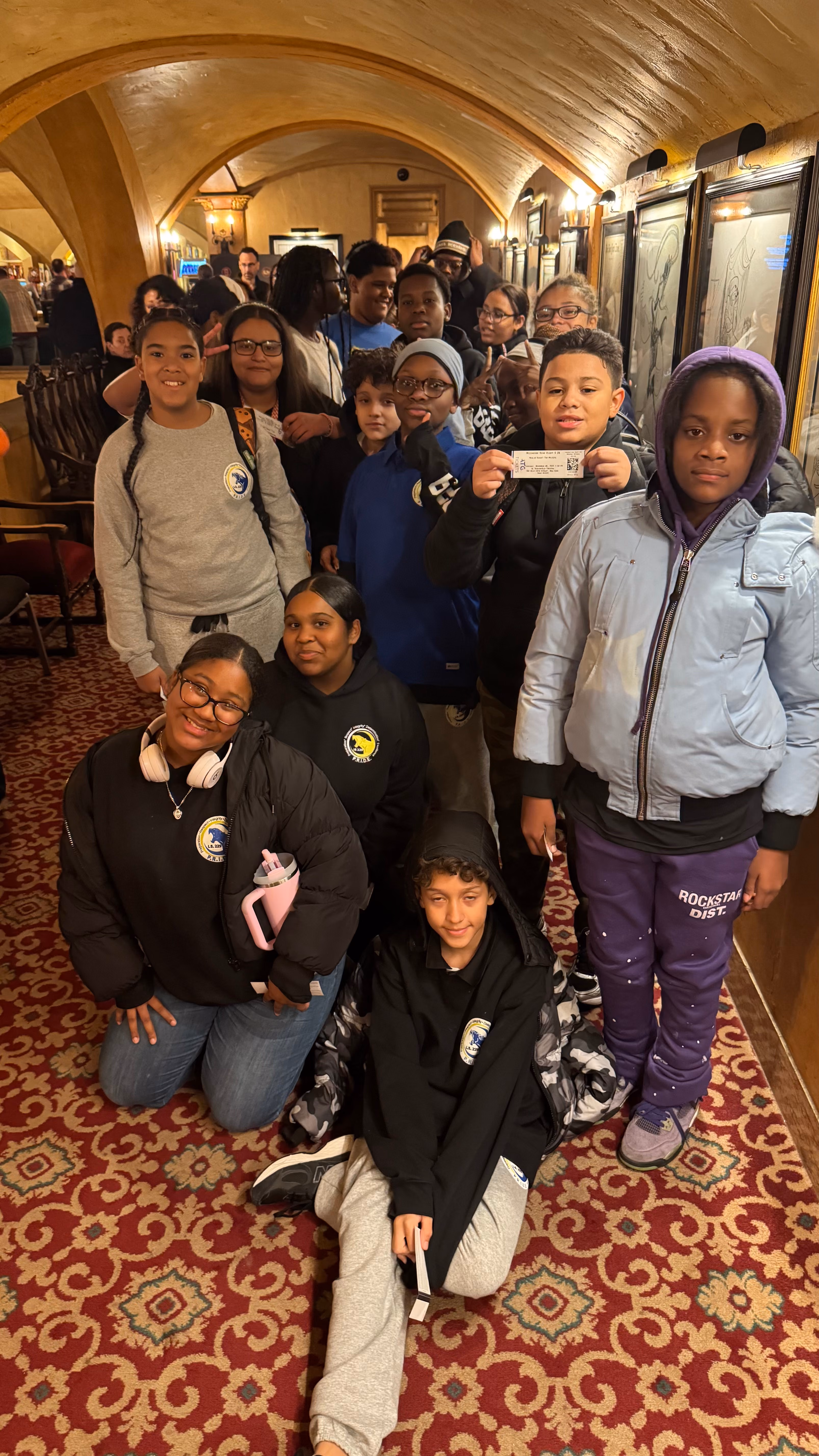 Students posing together inside a theater lobby on a field trip