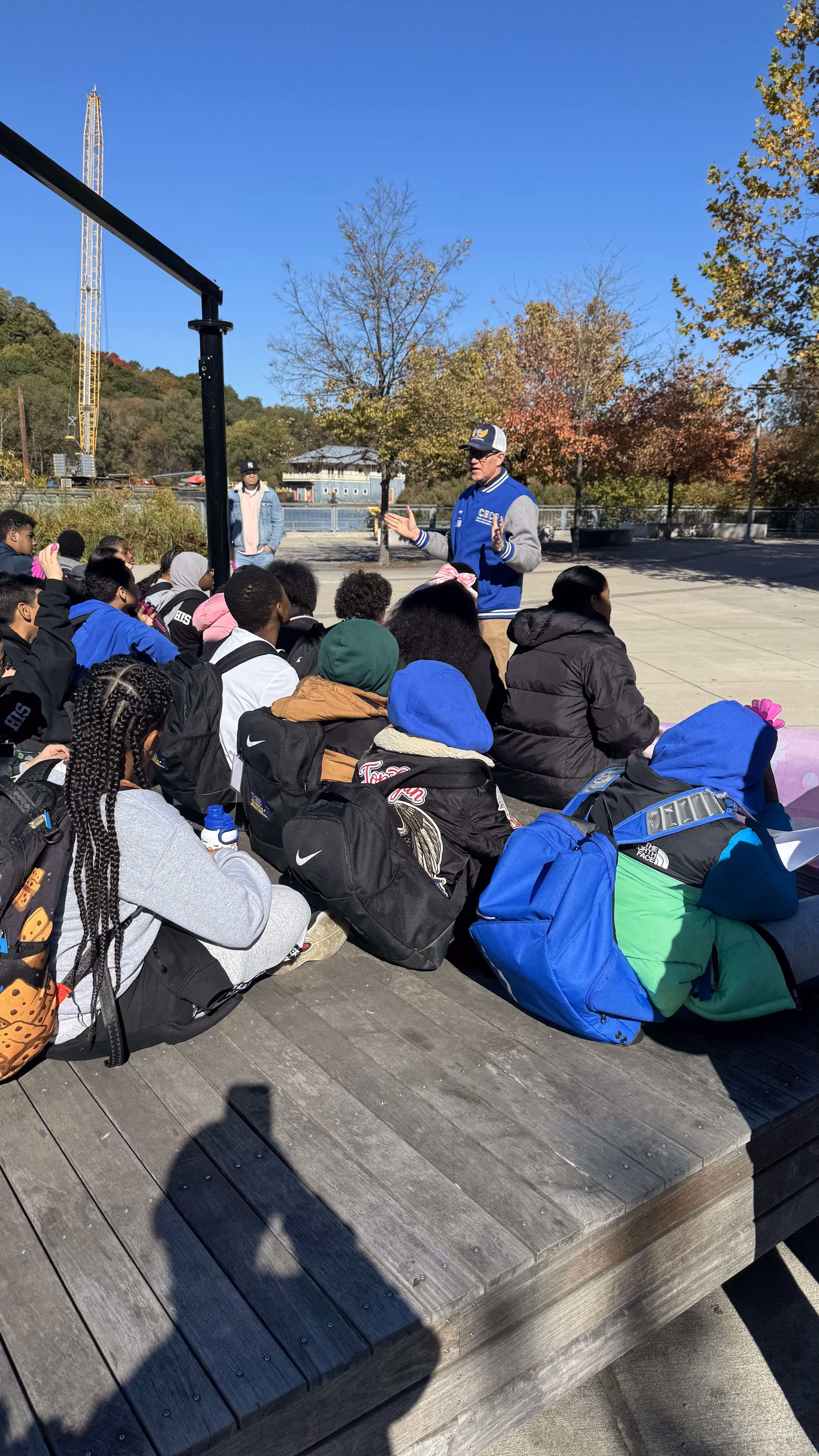 Students sitting outdoors listening to a speaker during a field trip