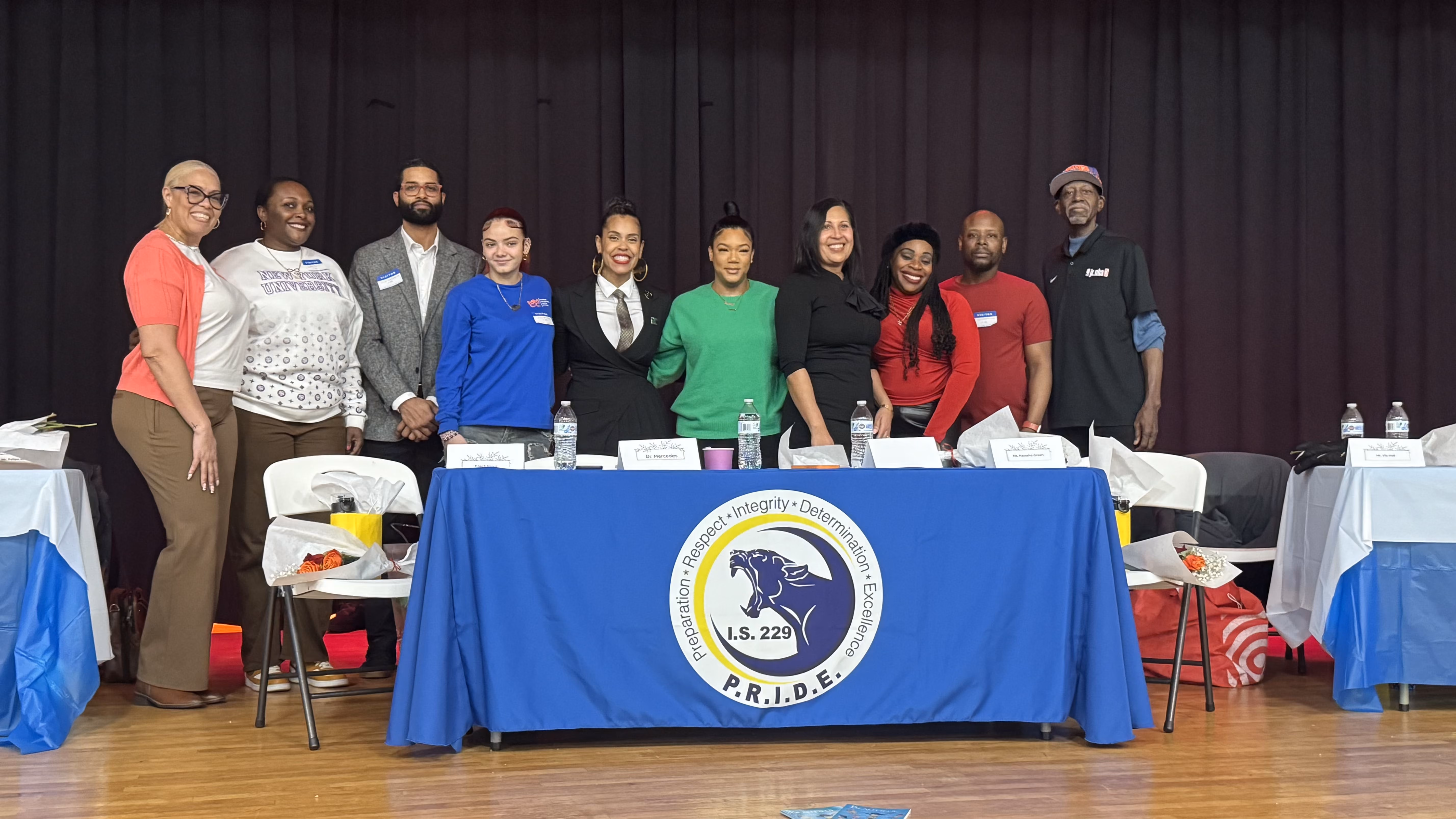 IS 229 staff and community members posing at school PRIDE event panel table